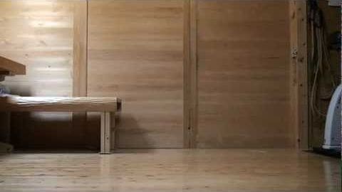 Wooden interior workshop or studio with tools leaning against wall, natural lighting from unseen windows, shades of light brown and beige dominating the scene