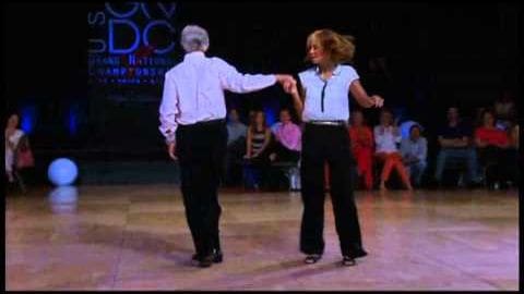 A dance couple at a competition, likely indoors.