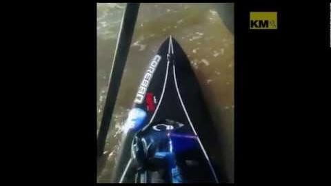 A speedboat with a black hull and white markings moving through a body of water, outdoors during daylight hours.