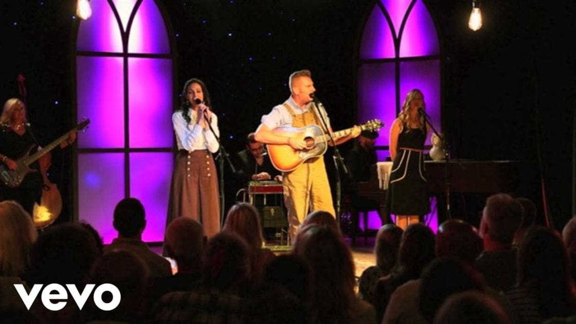 Musical performance with multiple performers in an indoor church-like setting at night.