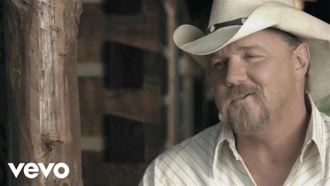 A middle-aged adult male wearing a striped button-up shirt in an indoor rustic setting with wooden beams.