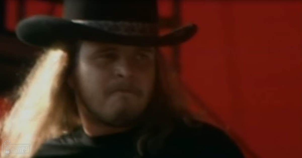 Middle-aged man wearing a black top hat indoors with red background elements.