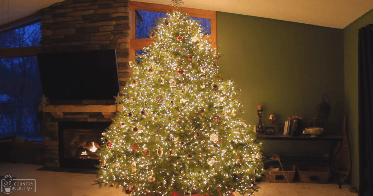 A cozy living room decorated for Christmas with a green wall, a stone fireplace, and a dark-toned shelf adorned with candles and ornaments.