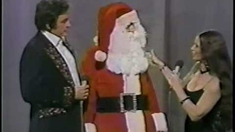 A festive Christmas-themed scene, possibly from a holiday special or performance with adults in formal attire indoors under controlled lighting.