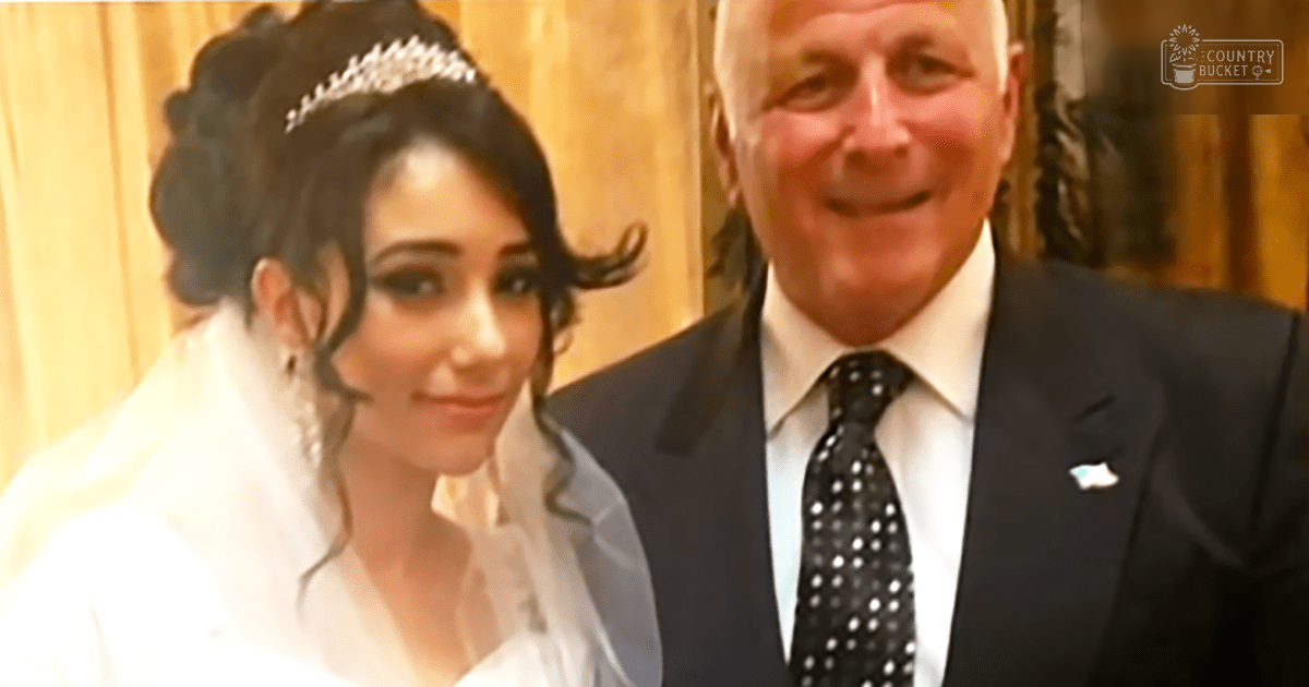 A bride and her father at a wedding ceremony indoors with wooden paneling, warm lighting, and a simple uncluttered background.