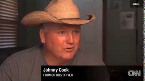 Johnny Cook, a middle-aged male former bus driver, stands indoors with a straw cowboy hat and neutral-toned attire against an office or home environment backdrop.
