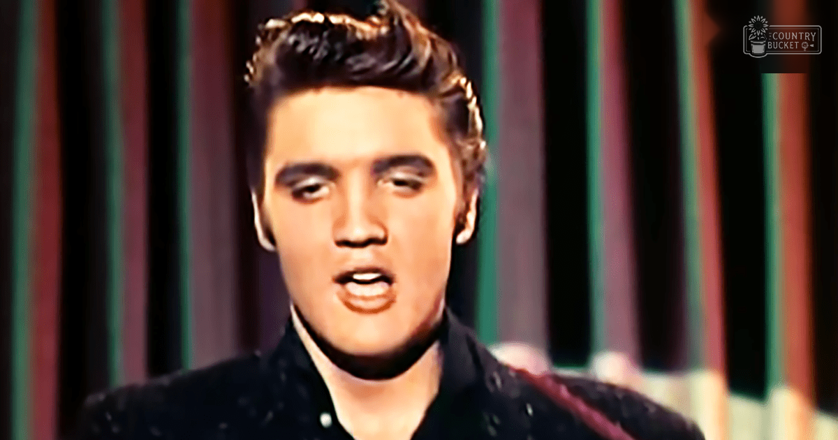 A young adult male in a studio setting wearing a dark-colored button-up shirt with a slim fit.