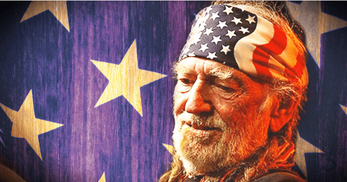 An older adult male wearing an American flag-patterned headband, indoors with a backdrop resembling an American flag motif.