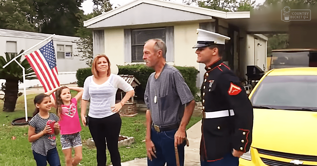 A family scene outside a residential home with children holding an American flag, adults in casual attire, and a yellow car partially visible.