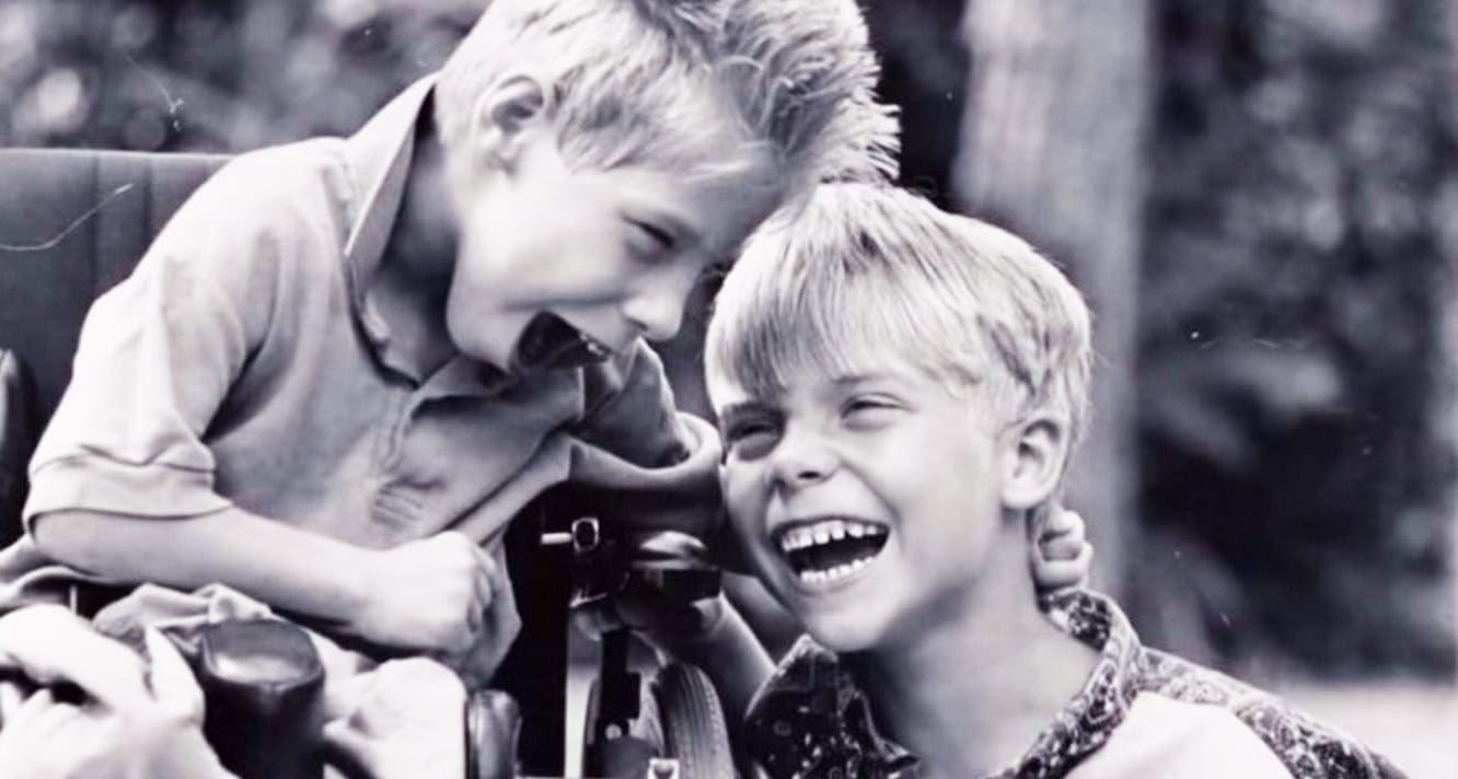 Two children in a mid-20th-century casual outfit in an outdoor setting with soft daylight and greenery.