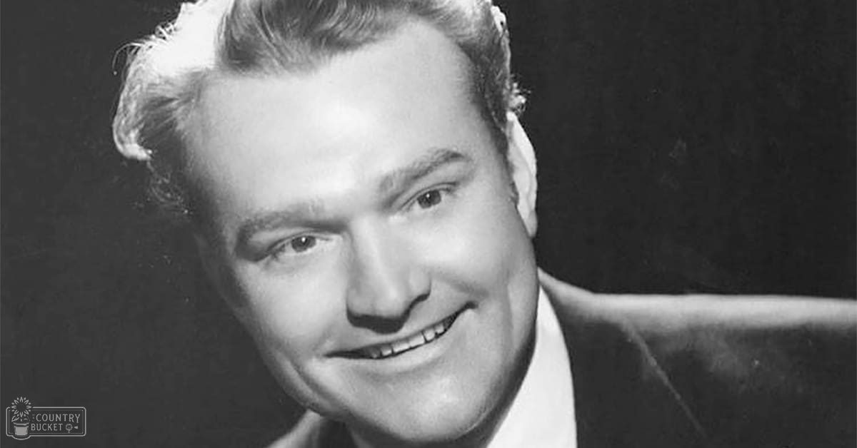 Middle-aged adult male in classic fit formal suit jacket, collared shirt against plain black backdrop for portrait photography.