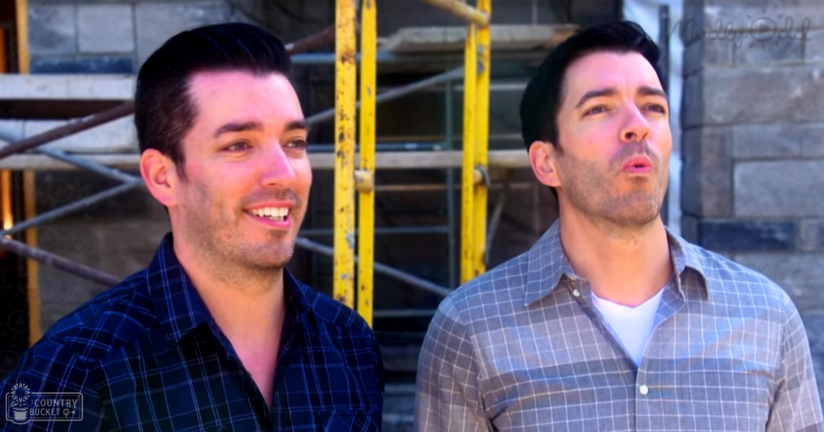 Two young adult males in casual plaid shirts stand against a backdrop of scaffolding on an urban construction site under natural light with spring or fall tones.