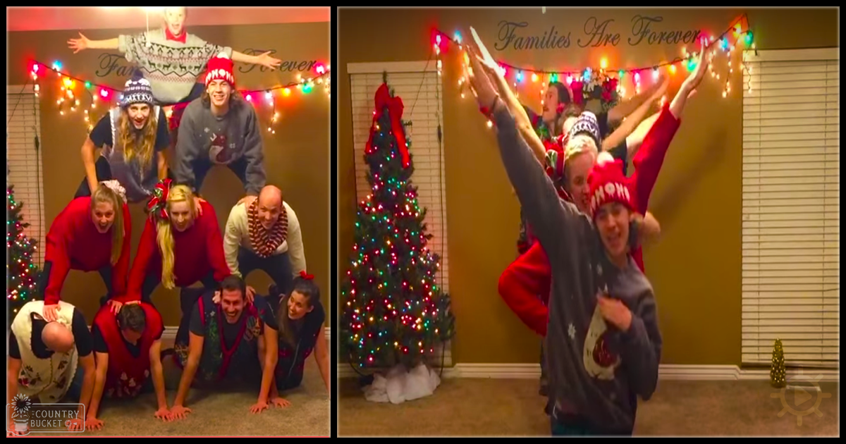A group photo of young adults in festive sweaters and red hats, decorated home interior during Christmas with a colorful tree and string lights.