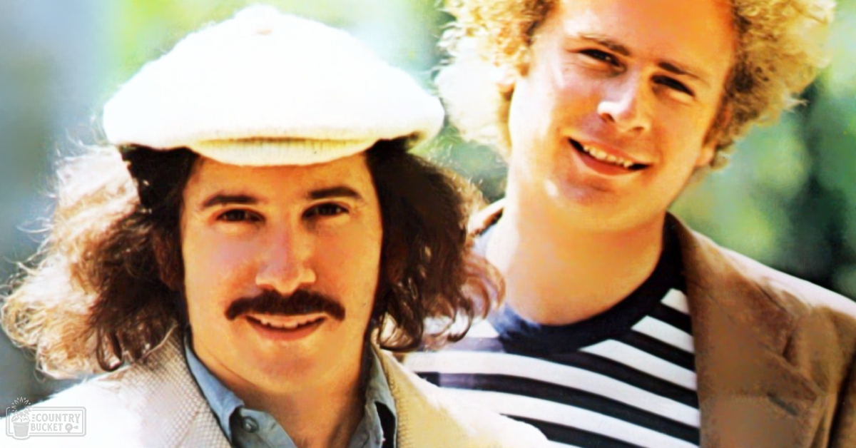 Two young adult males in casual attire outdoors with greenery in the background during daytime.