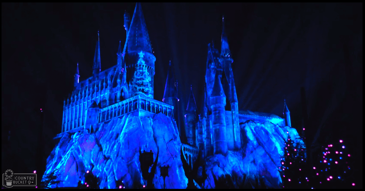 Hogwarts Castle at an amusement park, nighttime scene with blue lights and tree decorations