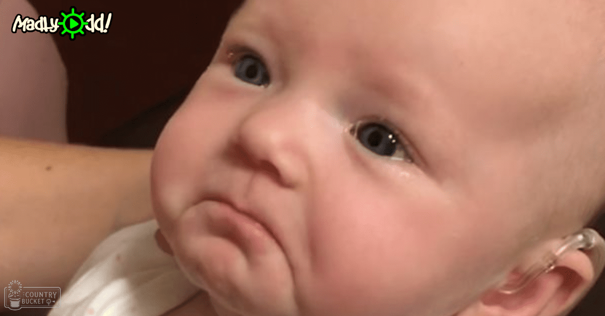 An infant wearing a white cotton garment indoors with natural light illuminating the scene