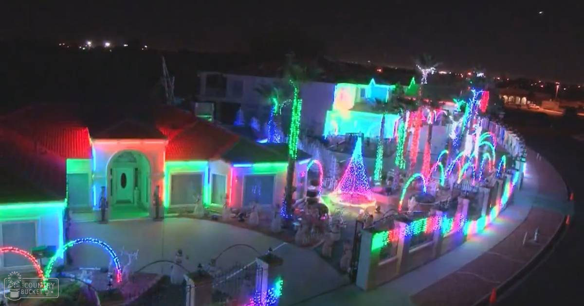 Houses adorned with vibrant Christmas lights and festive ornaments against a dark night sky during holiday season