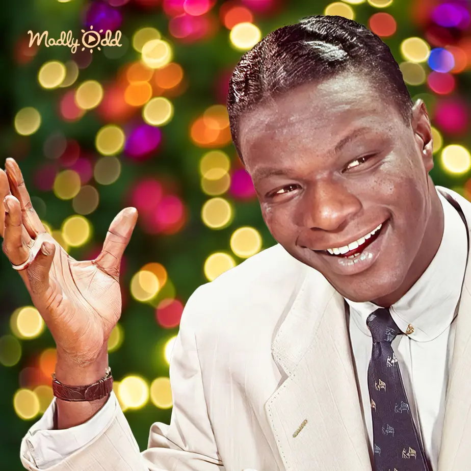 Adult male in a formal white suit with pinstripes, patterned tie, festive indoor setting with holiday lights.