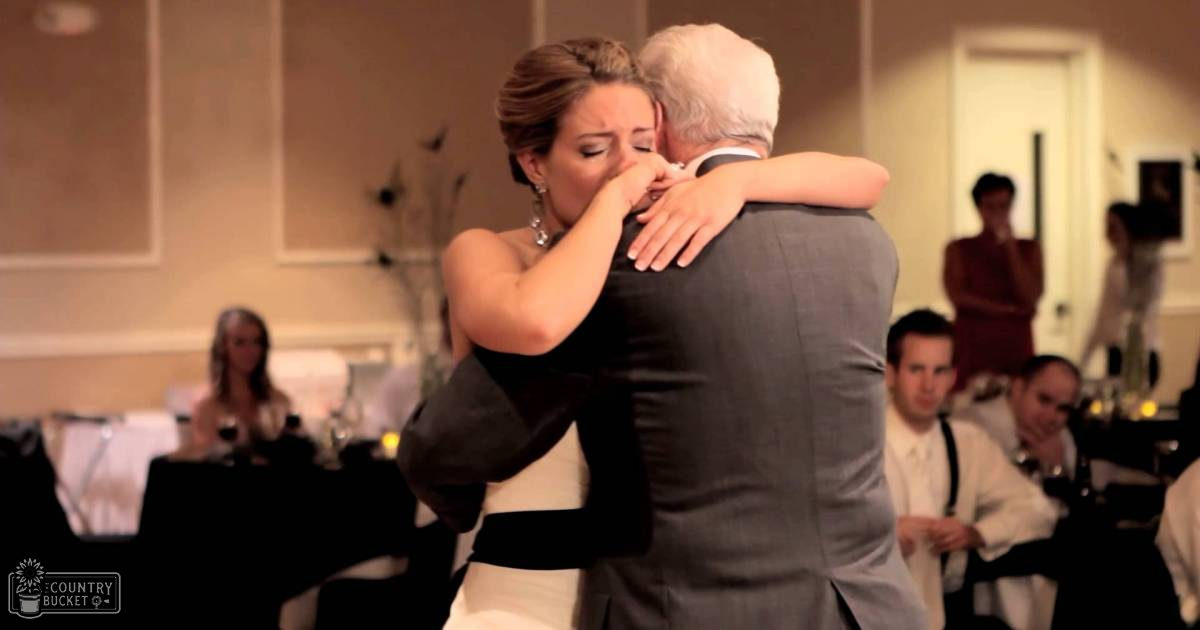 A bride dancing with her father at a wedding reception in an indoor banquet hall.
