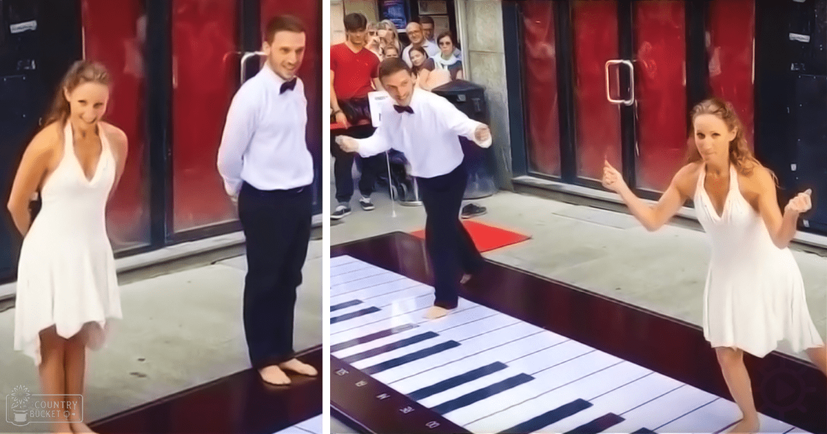 A couple dancing in front of a red door with glass panels on an outdoor stage during what appears to be late afternoon, with spectators watching the performance.