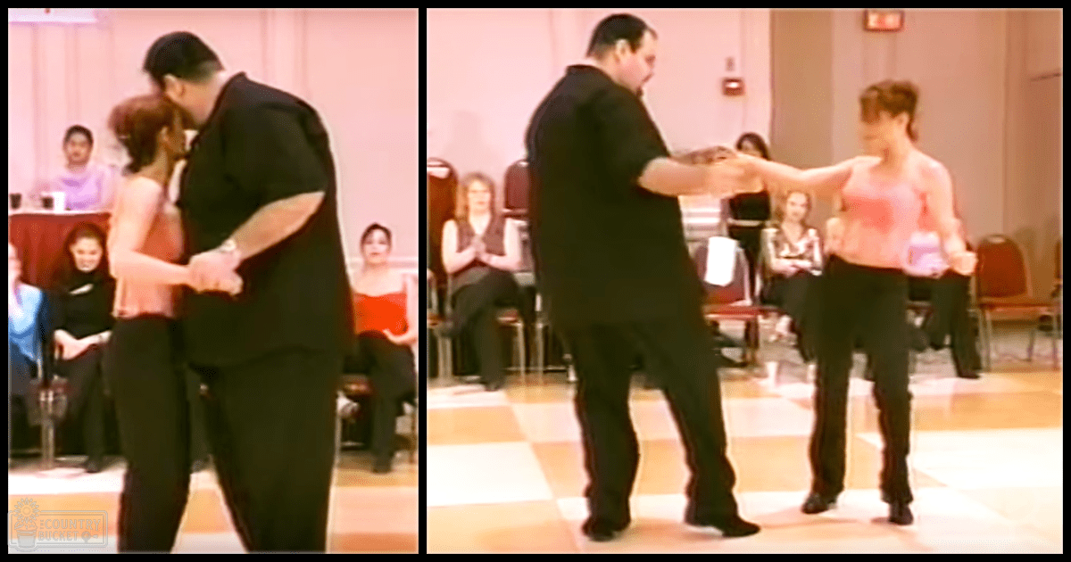 A couple dancing indoors in a dance hall with checkered tiles under artificial lighting.