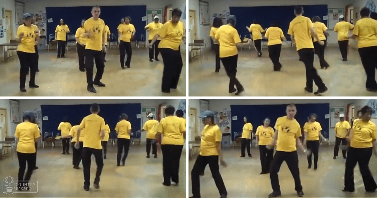 A group of older adults participating in a Tai Chi exercise class at an indoor community center with bright daylight and blue curtains.