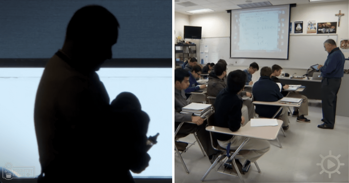 A classroom setting with an adult male teacher holding a tablet, surrounded by students wearing dark-colored jackets. White desks and chairs, a projection screen on the wall, and religious symbols in the background suggest an educational environment.