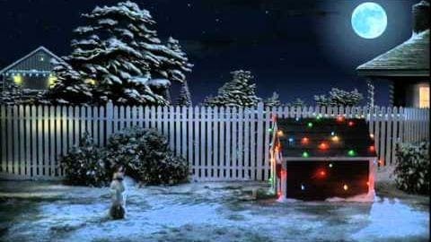 A young adult female in a snowy Christmas scene at night.
