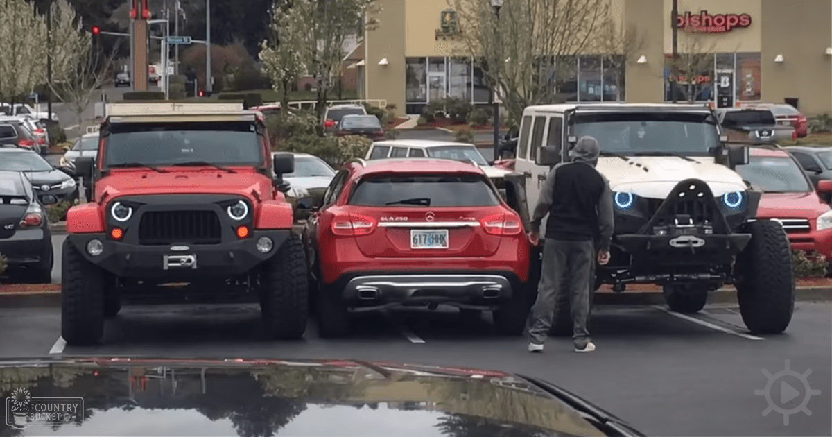 A parking lot scene with two Jeeps, a Mercedes-Benz GLA-Class car, and various parked vehicles in an outdoor shopping area during late fall or winter.