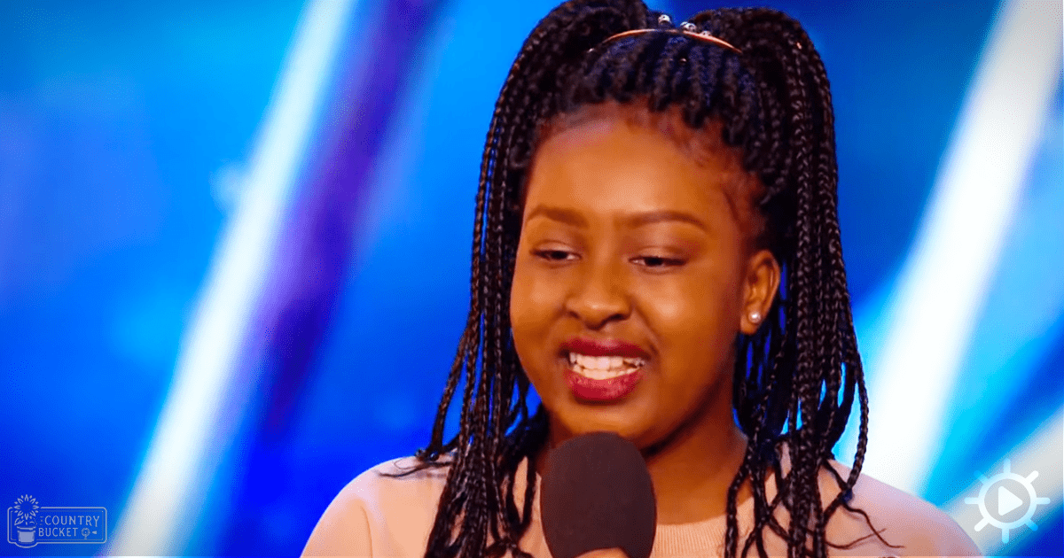 Young adult female in a white sleeveless top with braided hair, speaking into a microphone against a blue gradient backdrop.