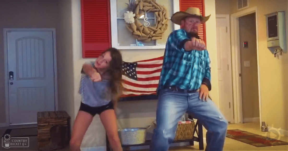 A middle-aged man and a young woman dancing in a home setting with rustic decor and warm lighting.