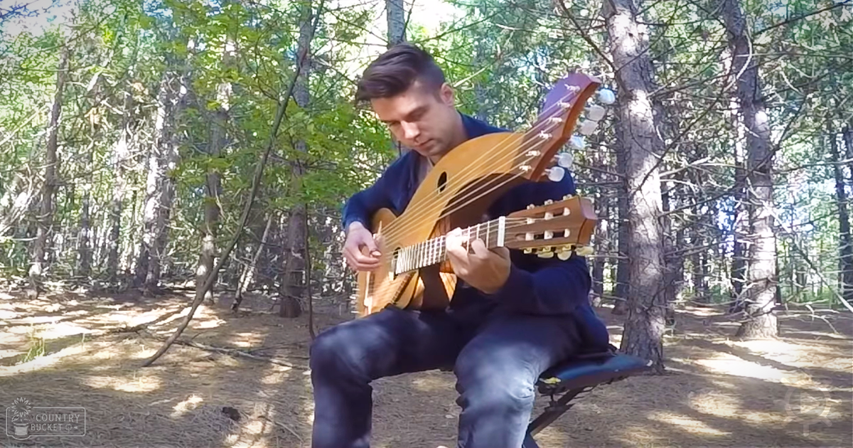 A young adult male playing an oud in a forest setting with dappled sunlight filtering through the trees.