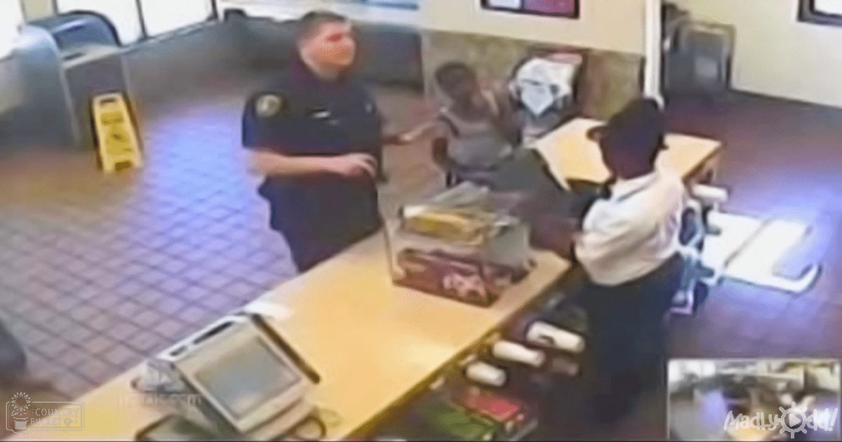 An adult male security guard in a dark uniform stands near an older female seated at a counter inside what appears to be a convenience store, with various items and a cash register visible.