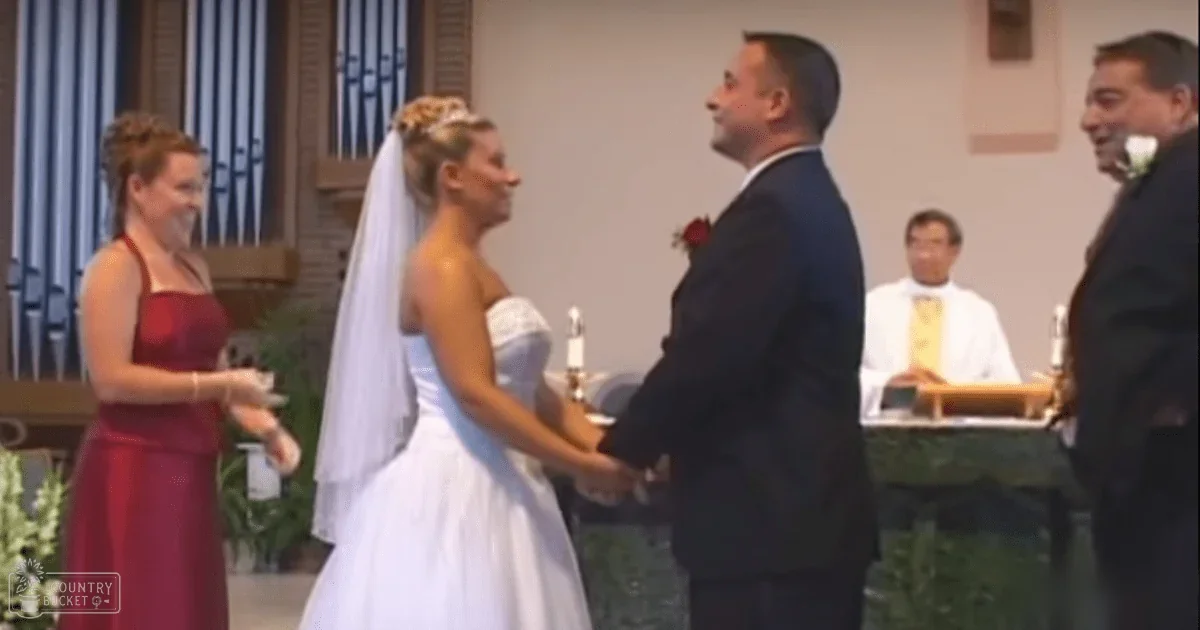 A bride and groom at a wedding ceremony in an indoor church setting with organ pipes visible in the background.