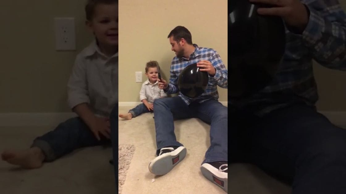 A middle-aged man and a toddler boy interacting indoors, surrounded by domestic details.