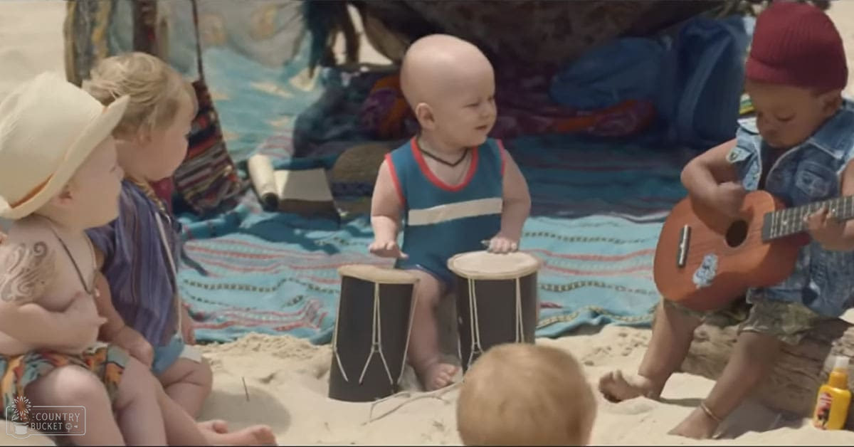 Children playing music on a sandy beach under bright midday sunlight.