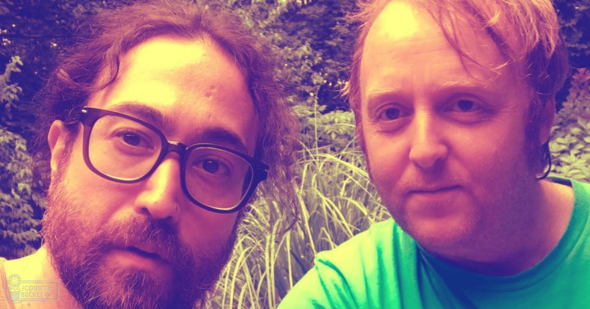 Two adults in a lush garden setting, wearing casual attire with vibrant green and white tones.