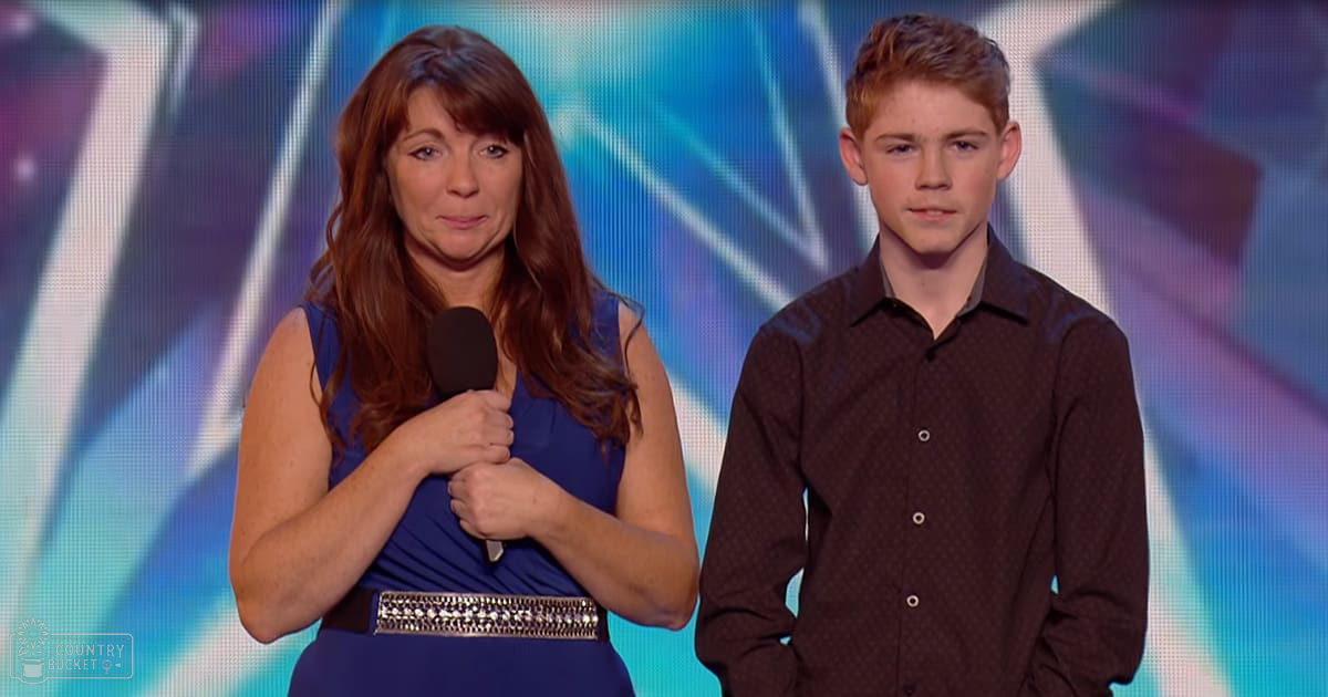An adult female singer holding a microphone, wearing a sleeveless blue dress with a decorative belt, accompanied by a teen boy in a dark, patterned shirt on stage under dynamic lighting.