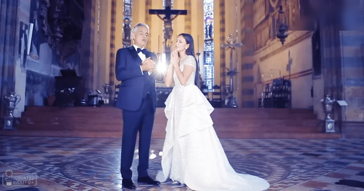 A bride and groom stand inside a grand Christian church during what appears to be a wedding ceremony, with soft natural light filtering through stained glass windows.
