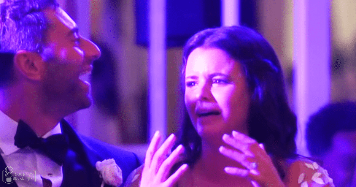 A couple dressed formally at an event venue with purple stage lighting and blurred background columns.