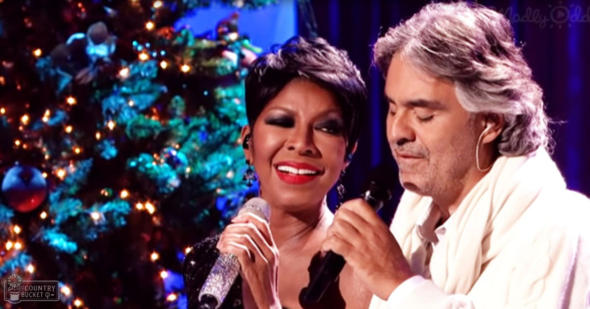 Two individuals performing on a stage with professional lighting and a decorated Christmas tree, suggesting a festive holiday performance.
