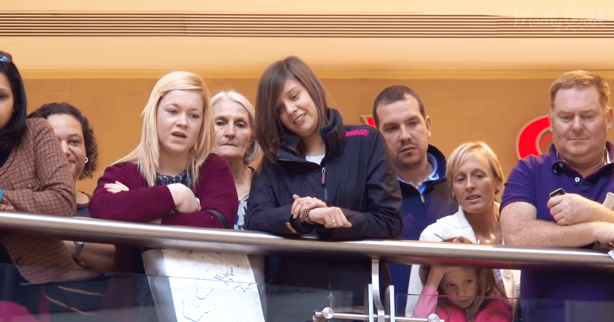 Group of adults in an indoor setting at a public event with various attire such as jackets and shirts.