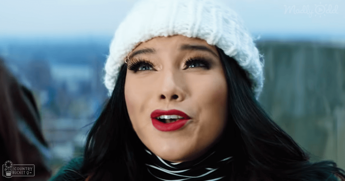 A young adult female wearing a white knitted hat and black and white striped turtleneck sweater, outdoors with an urban background, suggesting a cool season.