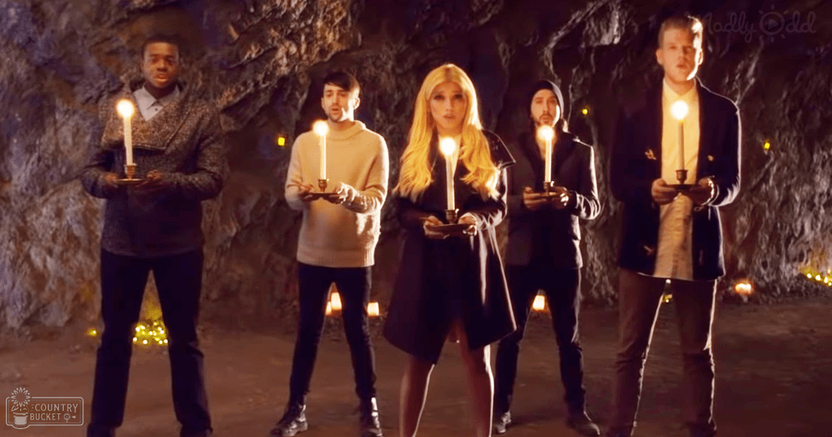 A group of young adults holding candles inside what seems like a cave or rocky environment.