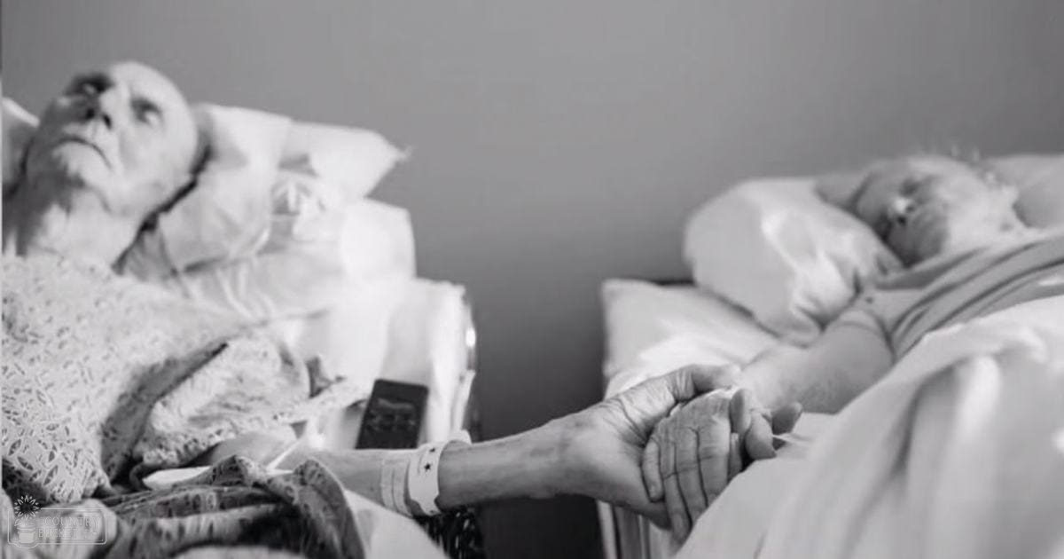 Two older adults in a bedroom setting, one wearing patterned pajamas or nightwear with lace details and soft fabric; another lying down partially covered by white bedding.