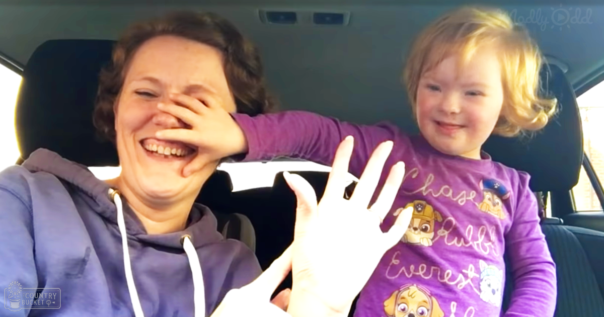 A woman and a toddler in purple clothing sit inside a vehicle during the day, with natural light illuminating their journey.