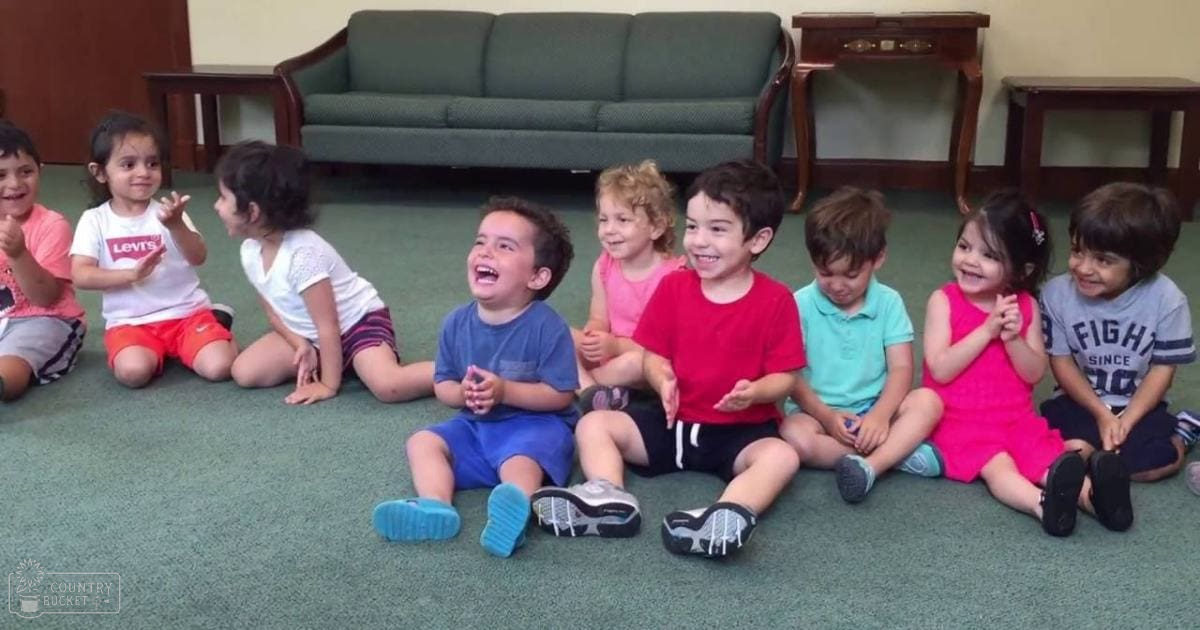Group of children in an indoor setting, wearing casual clothing; green sofa with cushions, wooden side tables, and a casual environment.