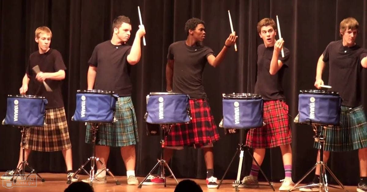Teenage boys performing with Yamaha drums at an indoor school or community hall setting.