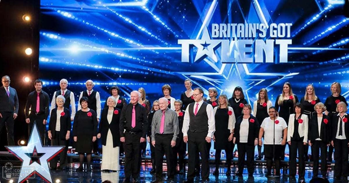 A group performance at 'Britain's Got Talent' in a studio setting, with adults wearing formal attire under blue stage lighting.