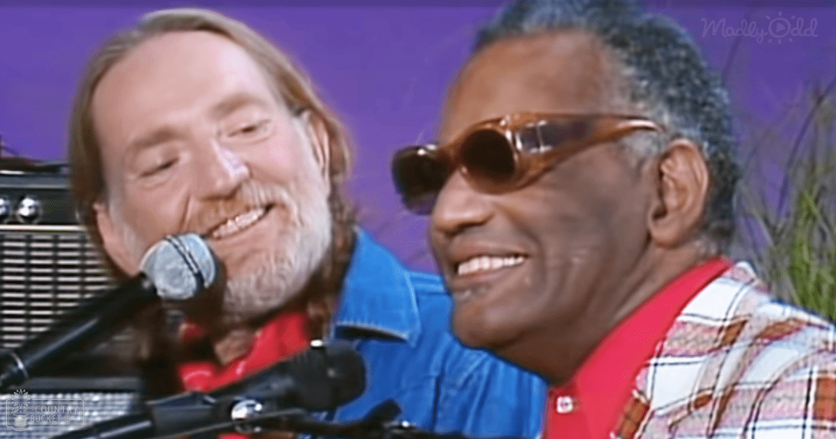 A middle-aged to older adult male singer wearing a blue denim jacket and red shirt performs alongside another man, both equipped with microphones, suggesting a musical performance or concert setting.